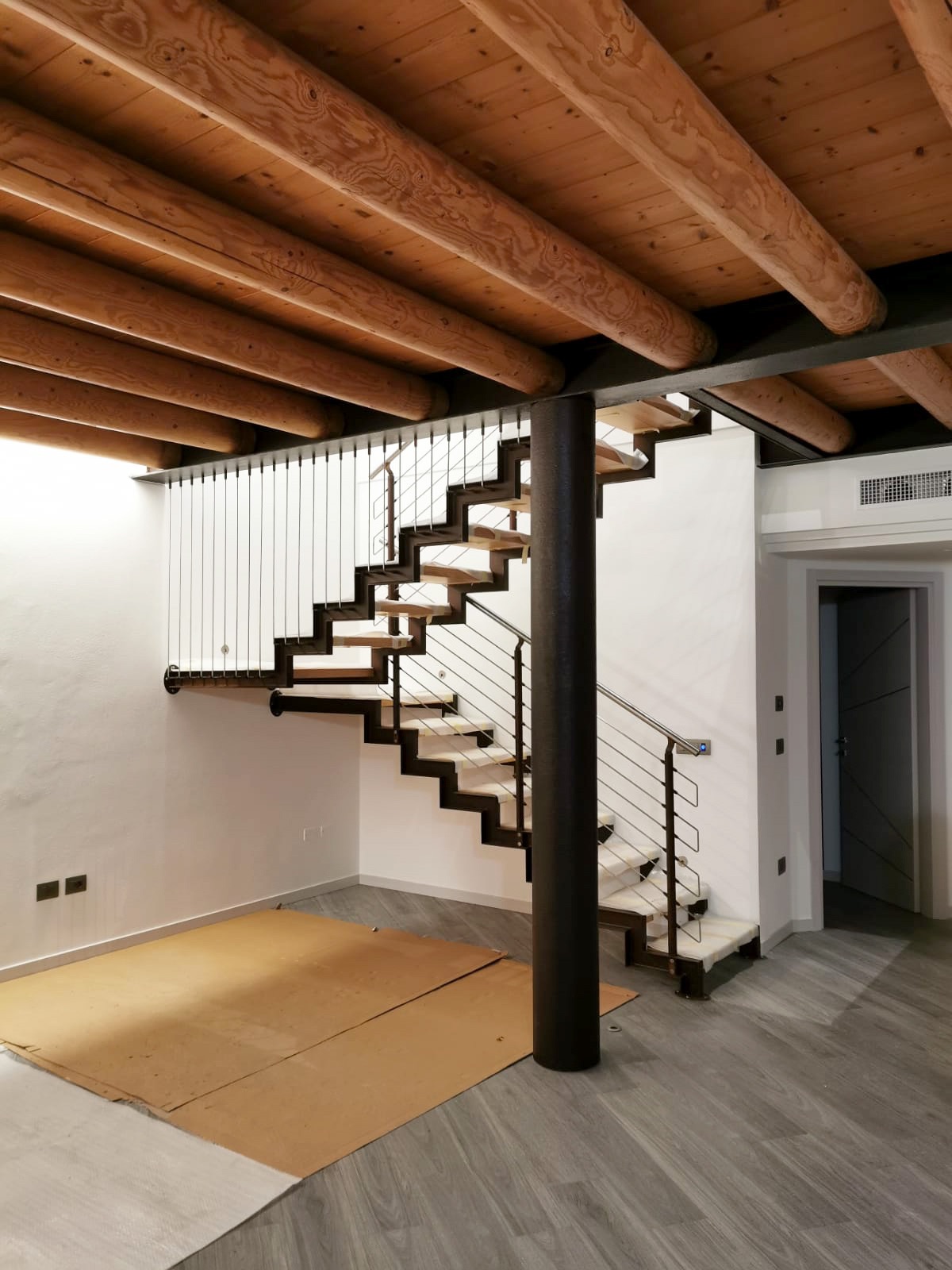 Scala a giorno con cosciali a scalino e ringhiera in acciaio.